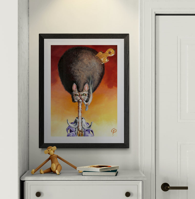 Framed artwork of a cat playing a guitar on a wall above a white dresser with a small figurine and books.