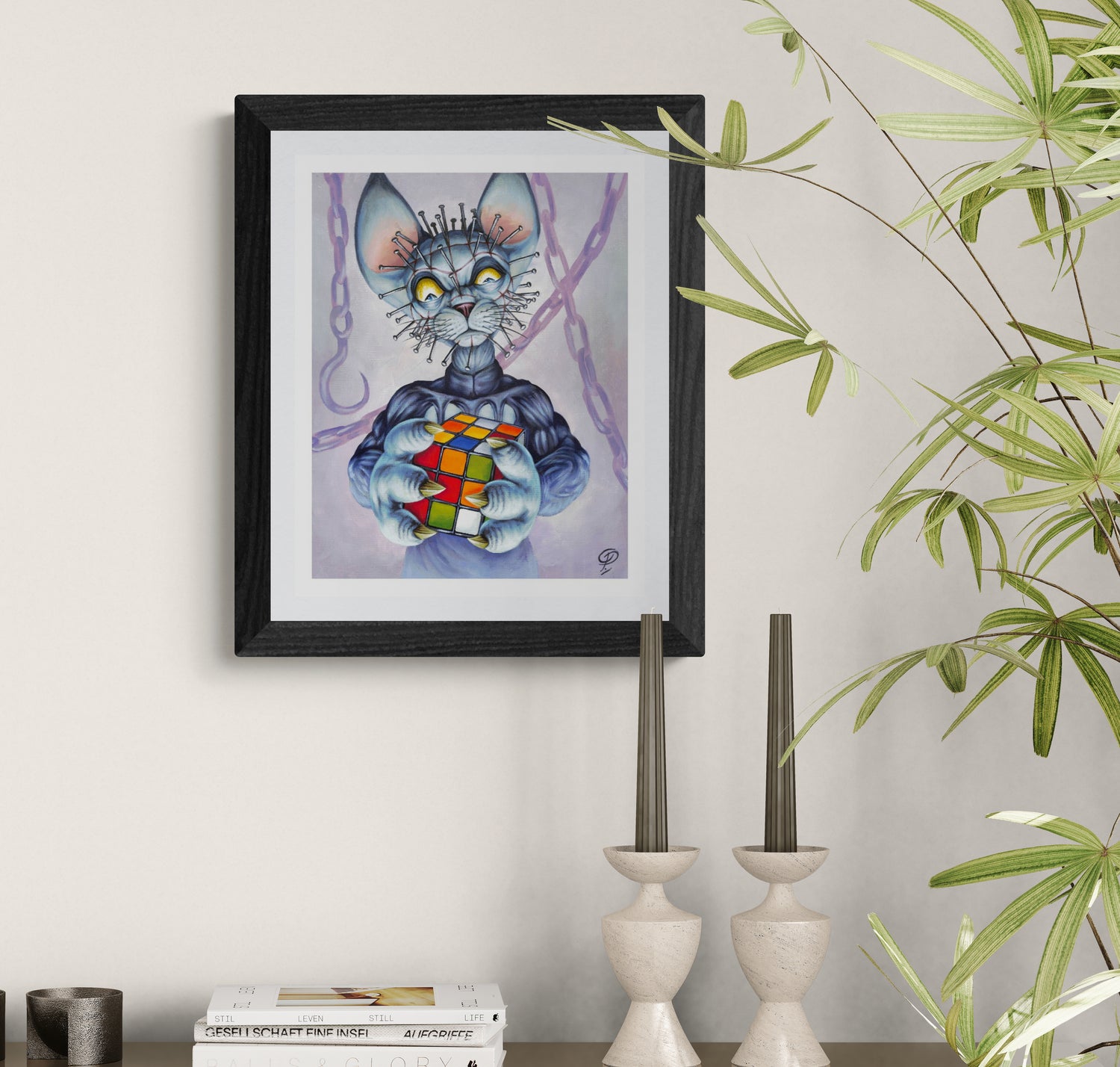 Framed artwork of a cat creature holding a Rubik's Cube on a wall with decorative elements.