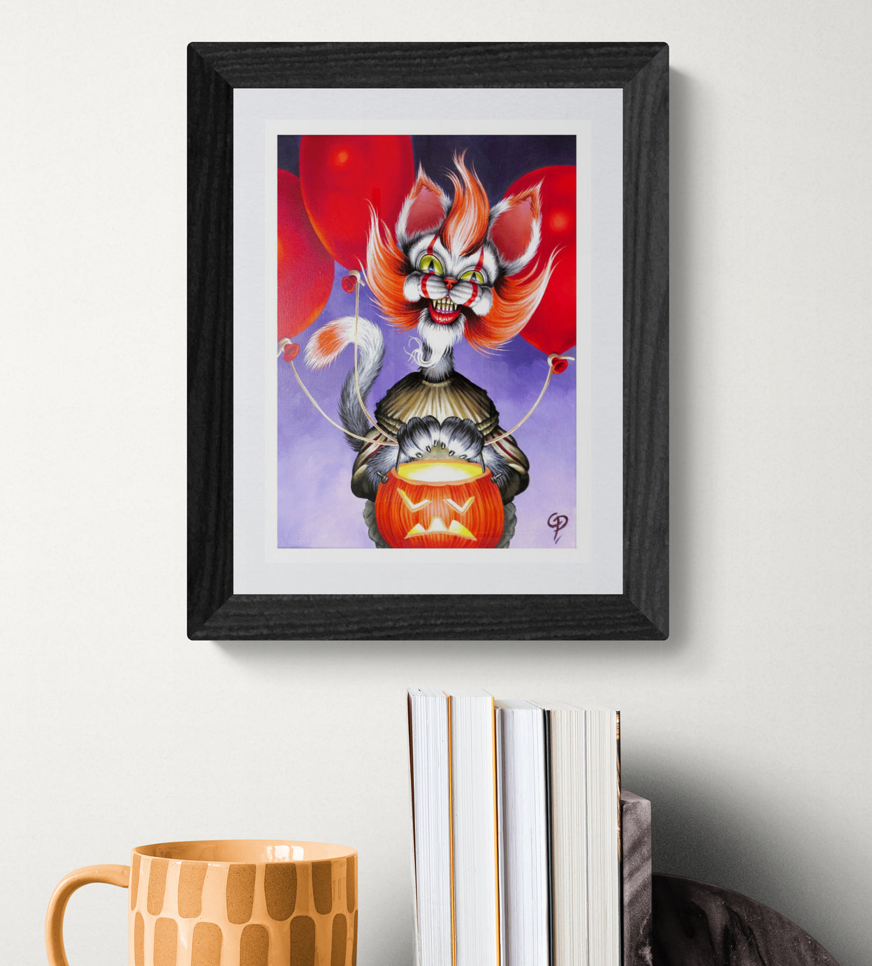Framed artwork of a colorful cat character with red hair and a pumpkin on a white wall.