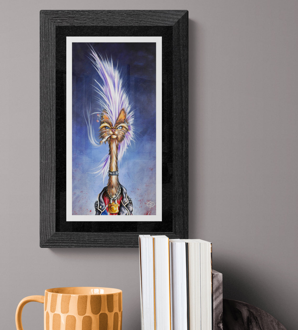 Framed artwork of a stylized punk cat on a gray wall with books and a mug below.