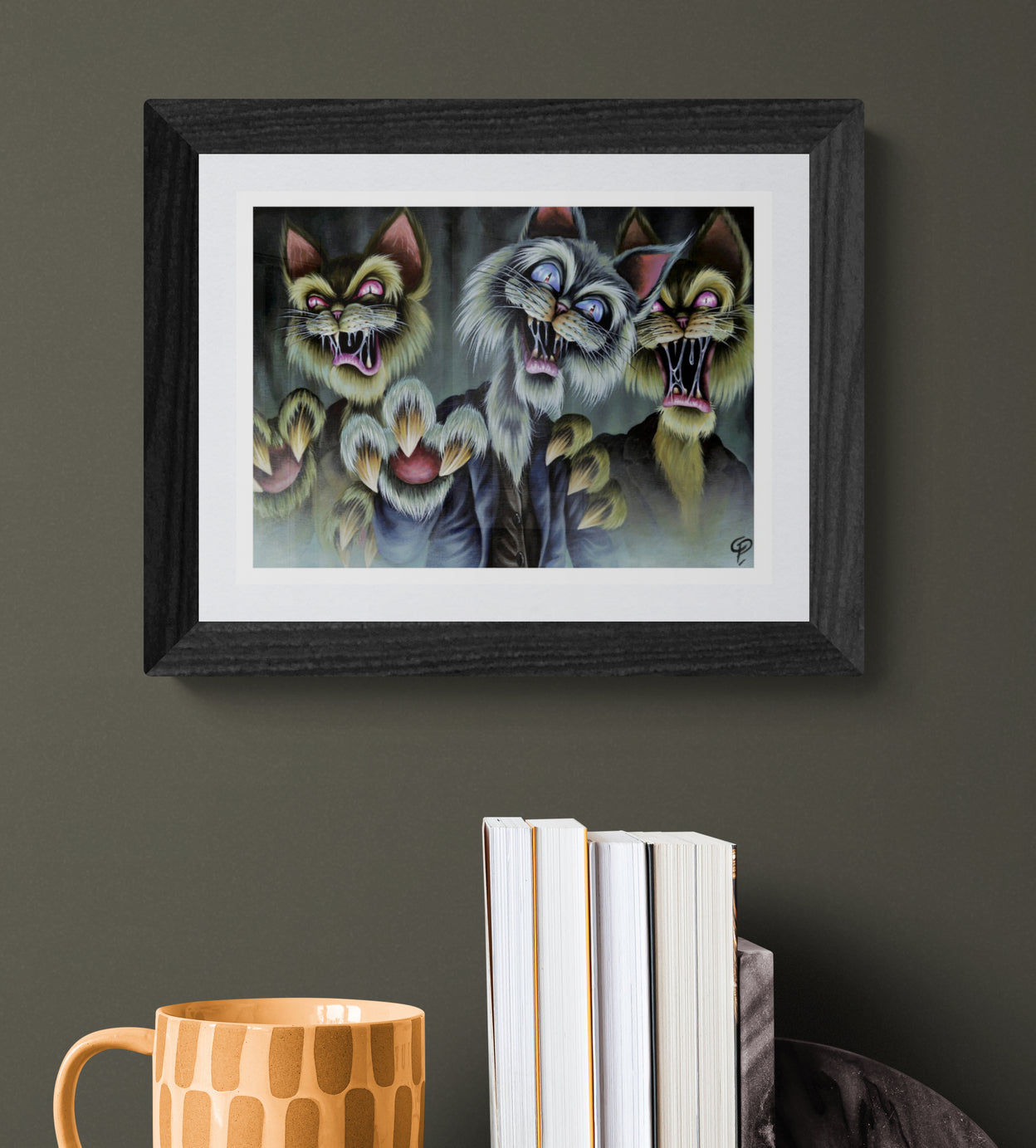 Framed artwork of three cartoonish zombie cats with open mouths on a dark wall.